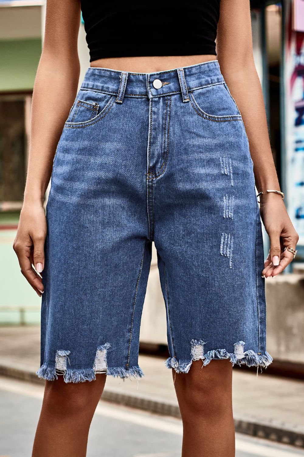 Women's high-waisted denim shorts with buttons, pockets, and raw hems.