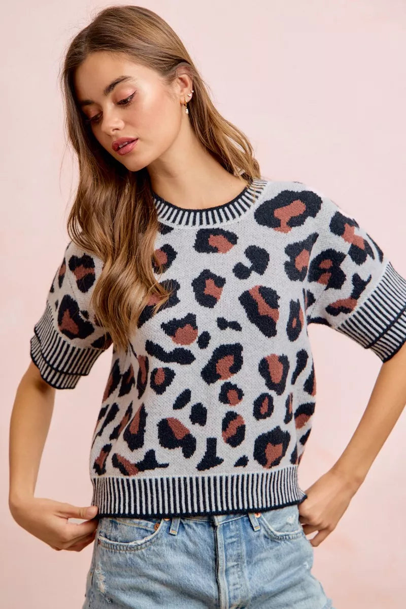 Front view of a light gray leopard print knit top with hands at the hem.