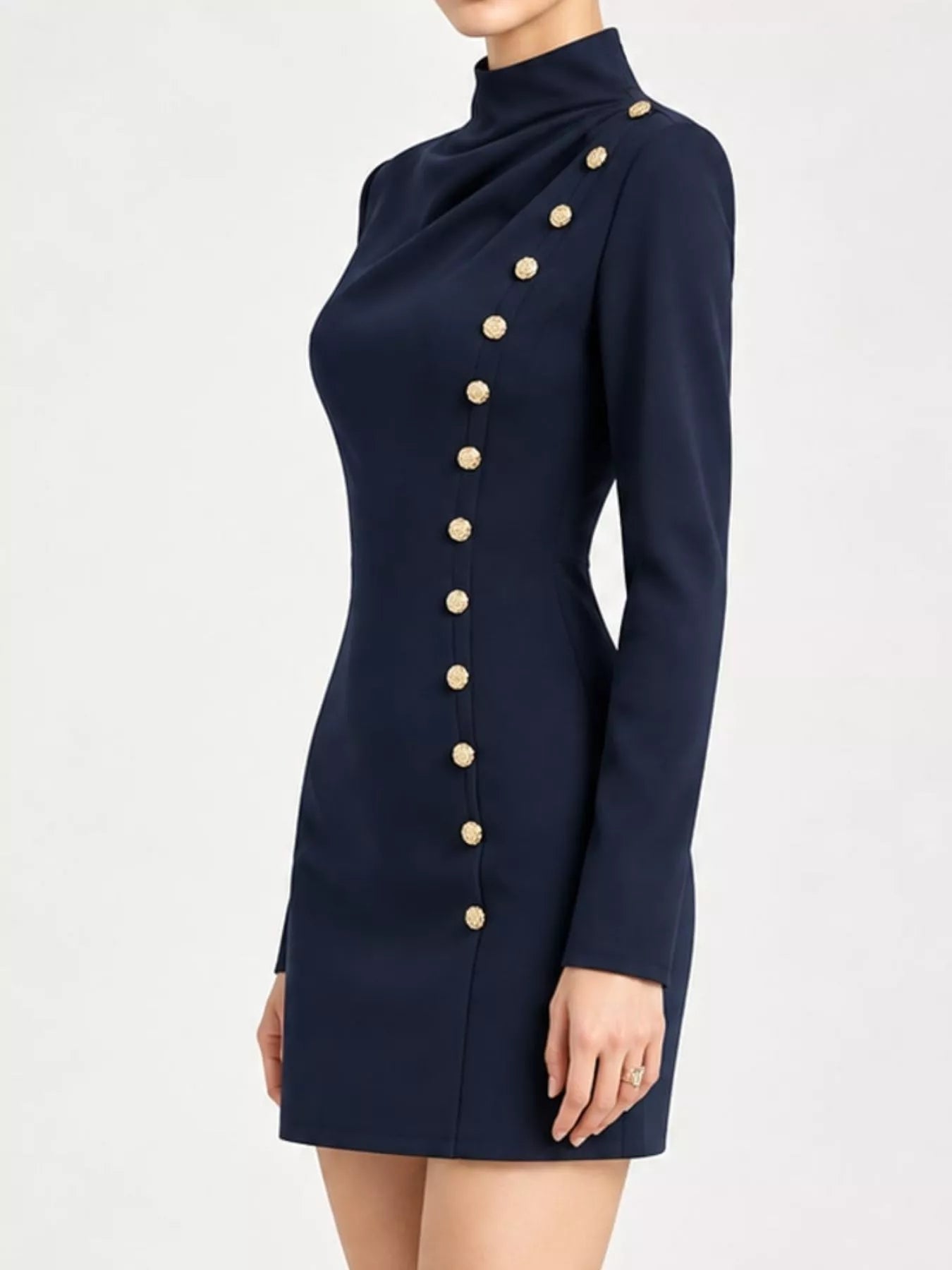 Side view of model in studio wearing navy mock neck mini dress with gold decorative buttons