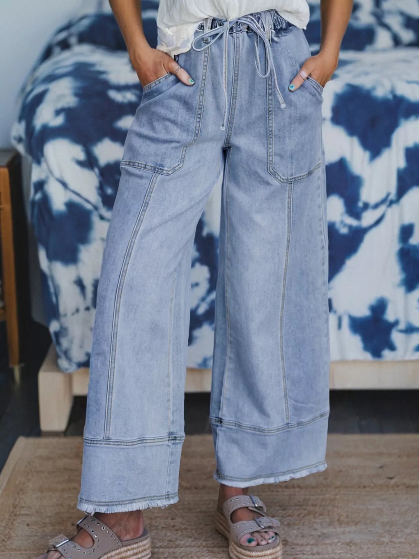 Women's wide-leg jeans with a drawstring waist, raw hems, and pockets.