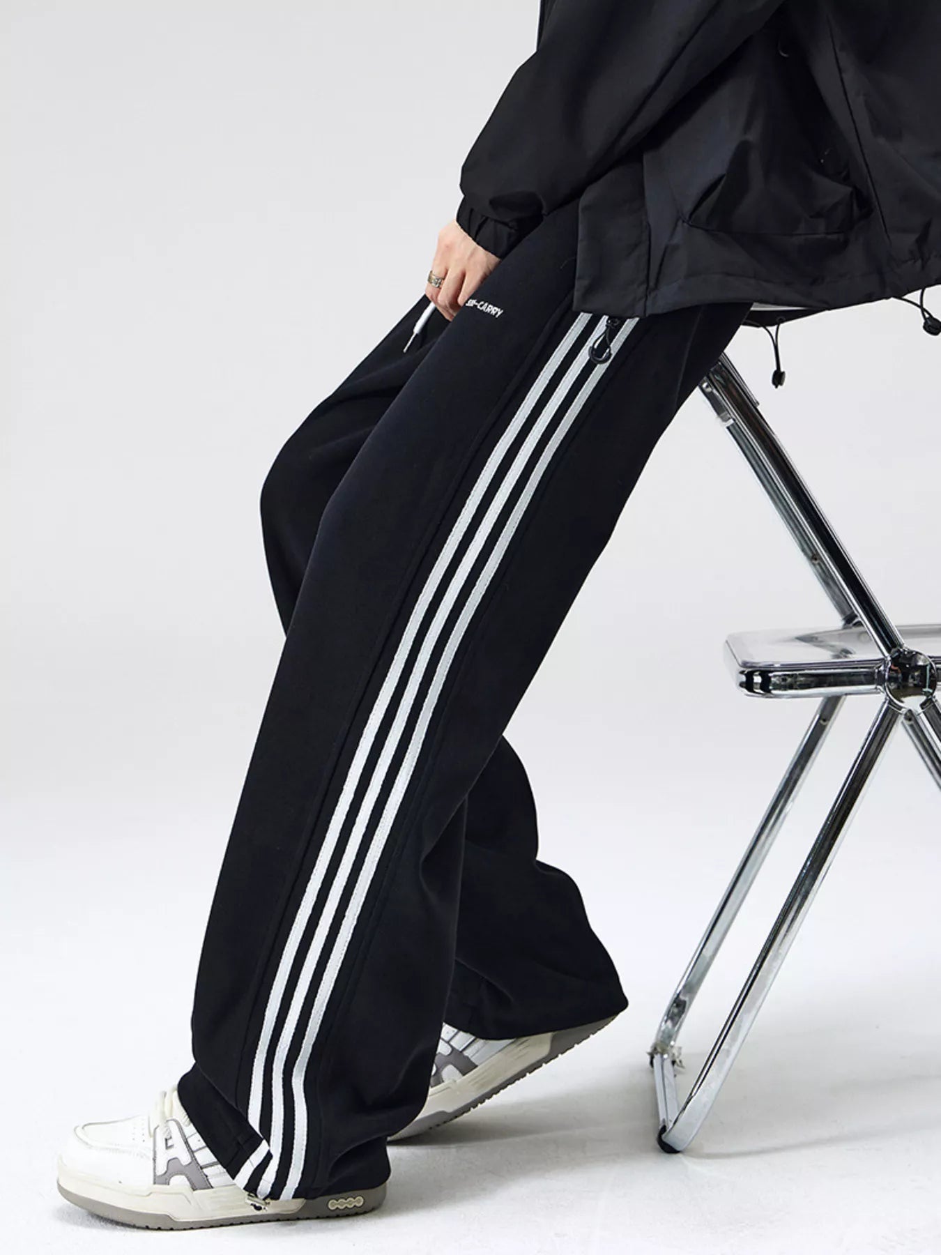 Men's black relaxed-fit pants with side stripes, a drawstring waist and pockets.