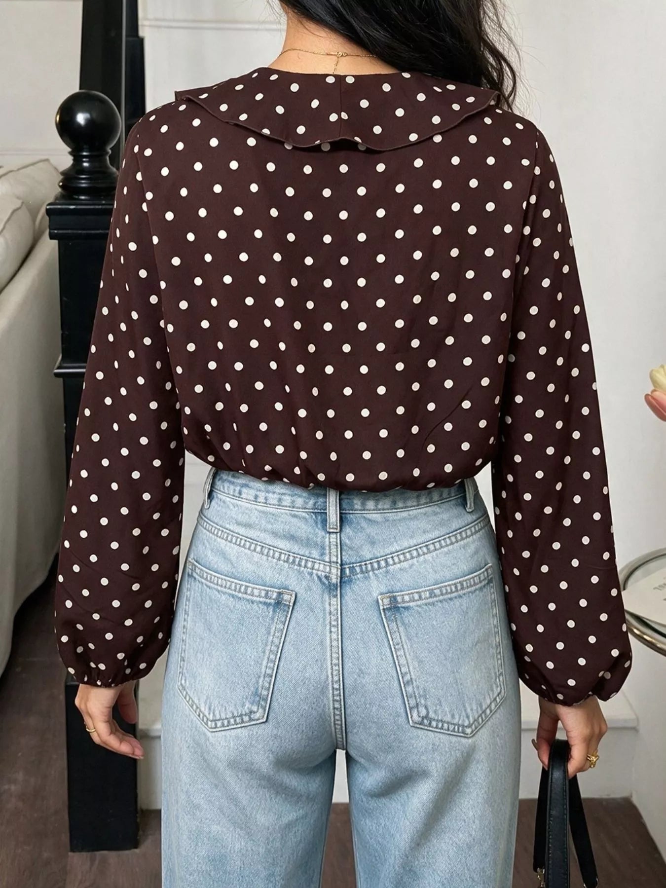 Back view of a coffee brown polka dot bodysuit with long sleeves and a ruffled collar