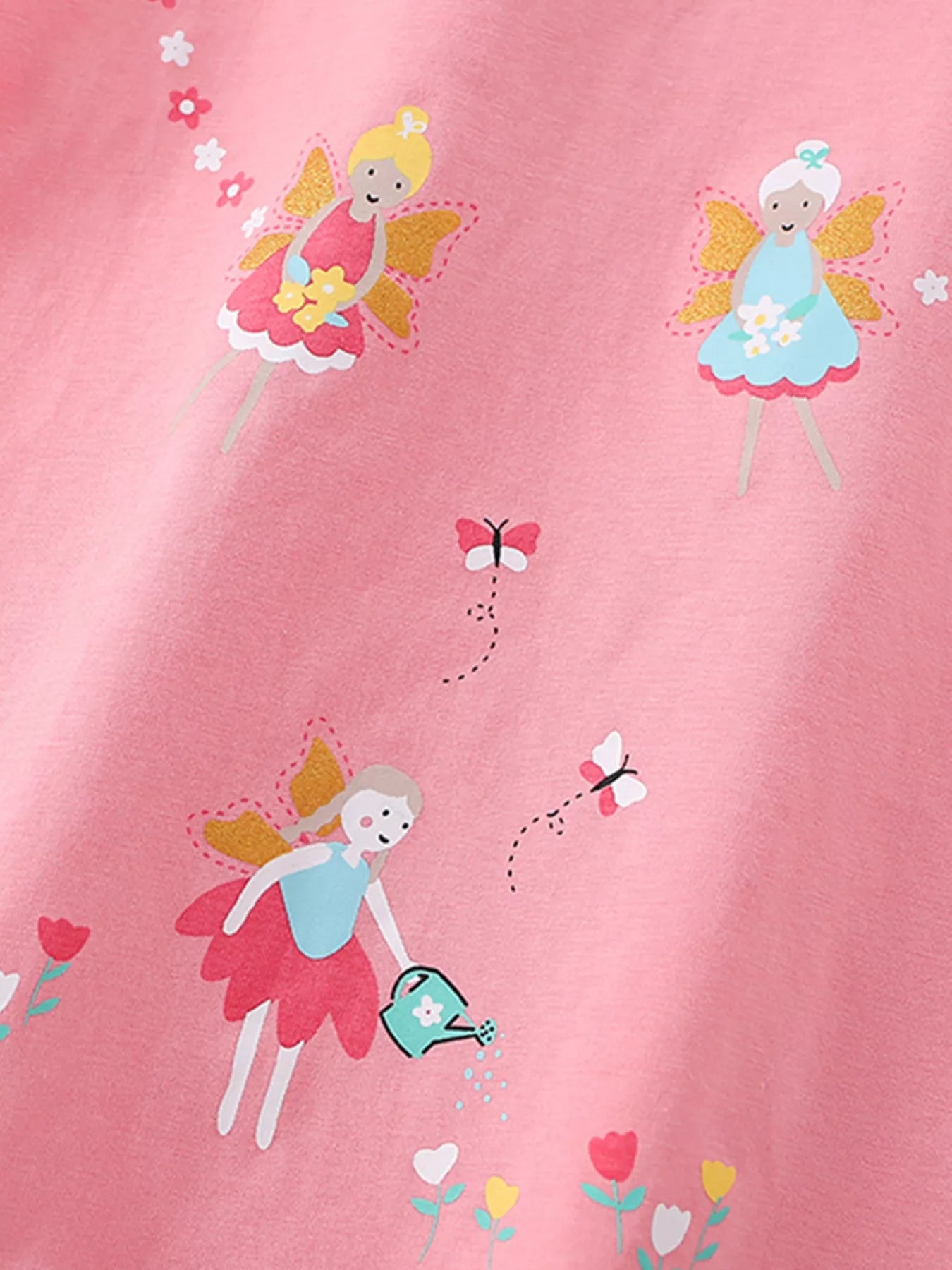 Close view of the fairy print with gold wings, butterflies and a watering can on pink fabric