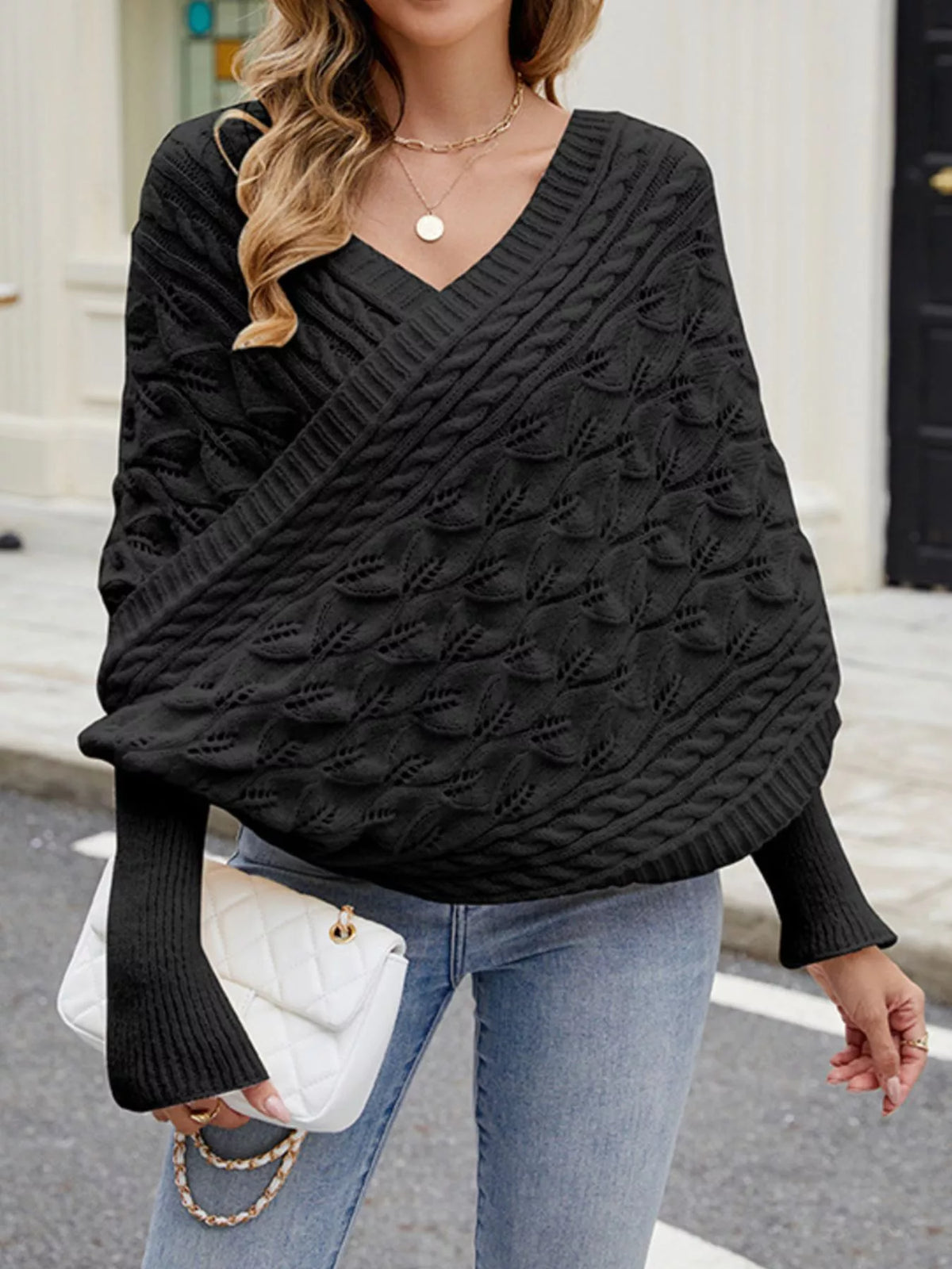 Front view of black cable knit batwing sweater with V neckline and leaf pattern.