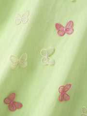 Close view of pink and white butterfly appliques scattered across the light green children's tee
