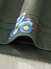 Close-up fabric detail showing a blue and yellow tractor print on army green polo shirt