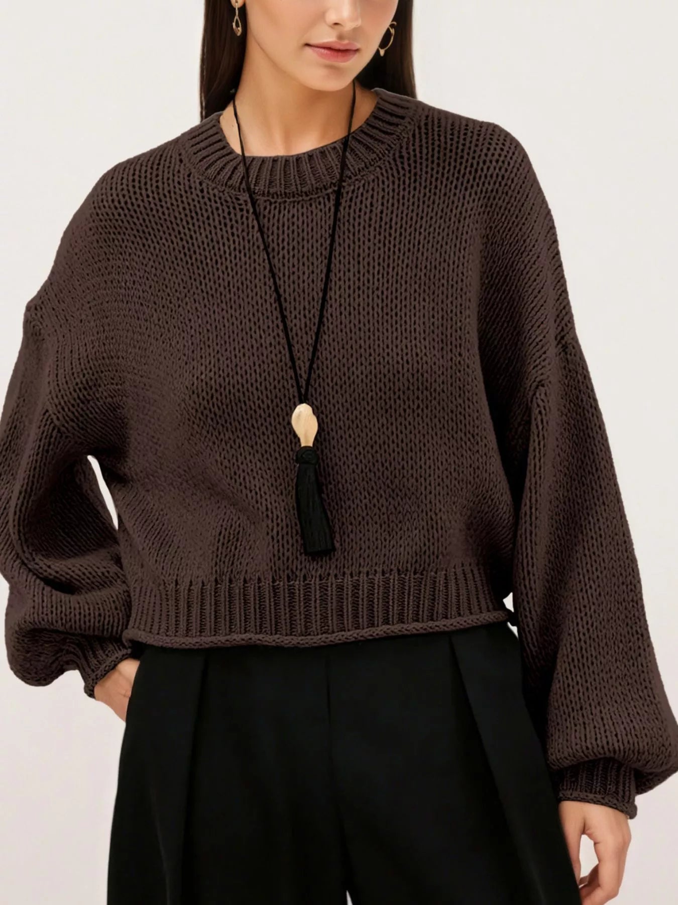 Close on-model front view of a brown oversized chunky knit sweater with ribbed hem