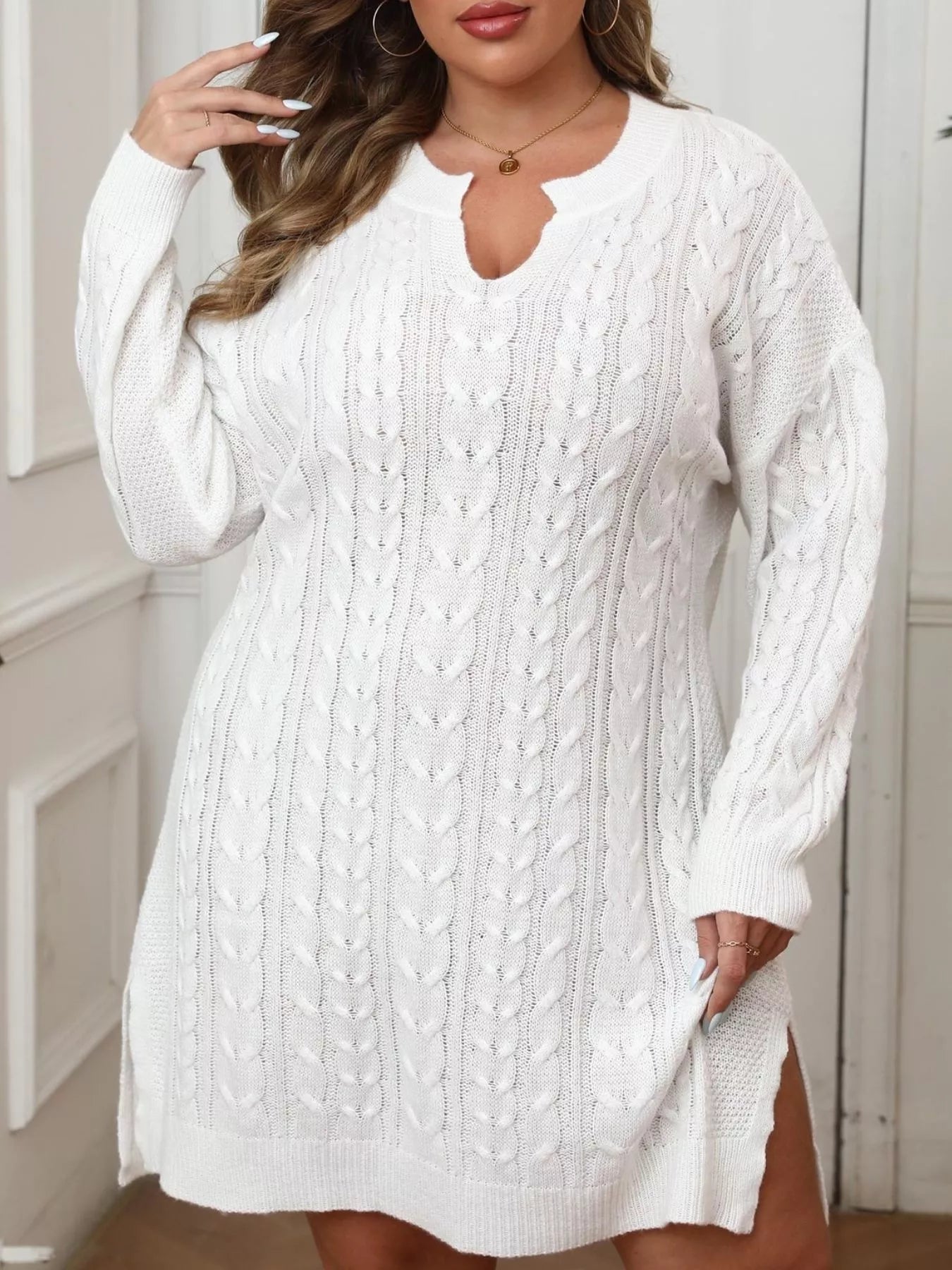 Front view of white cable knit sweater dress with side slit and notched neckline