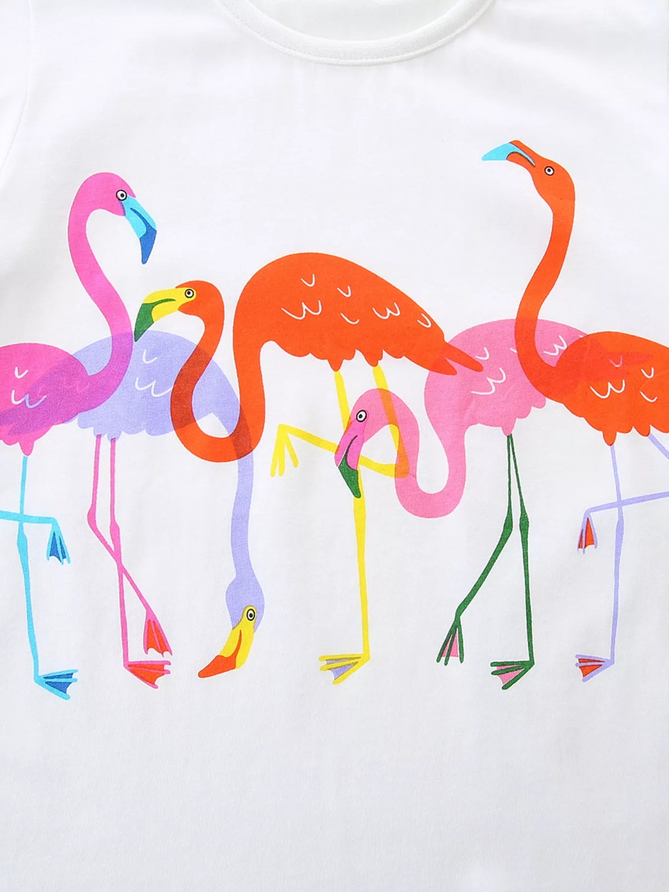 Close-up print detail showing pink orange and purple flamingos on white fabric