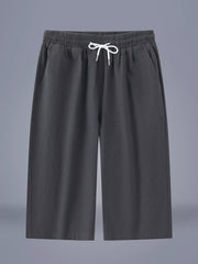 Men's dark gray cropped casual pants with a drawstring waist and pockets.