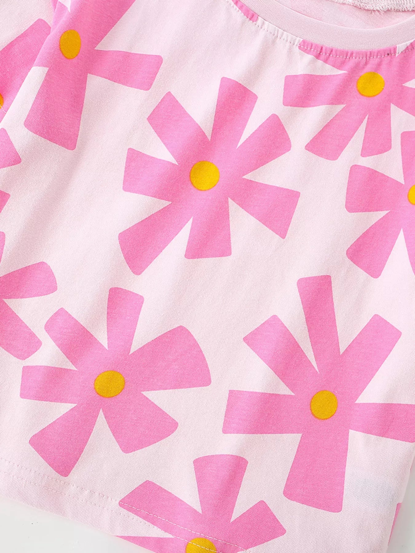 Close-up of pink floral print and hem stitching on light pink children's t-shirt