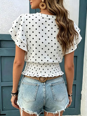 Back view of white polka dot blouse with ruffled sleeves and smocked peplum hem