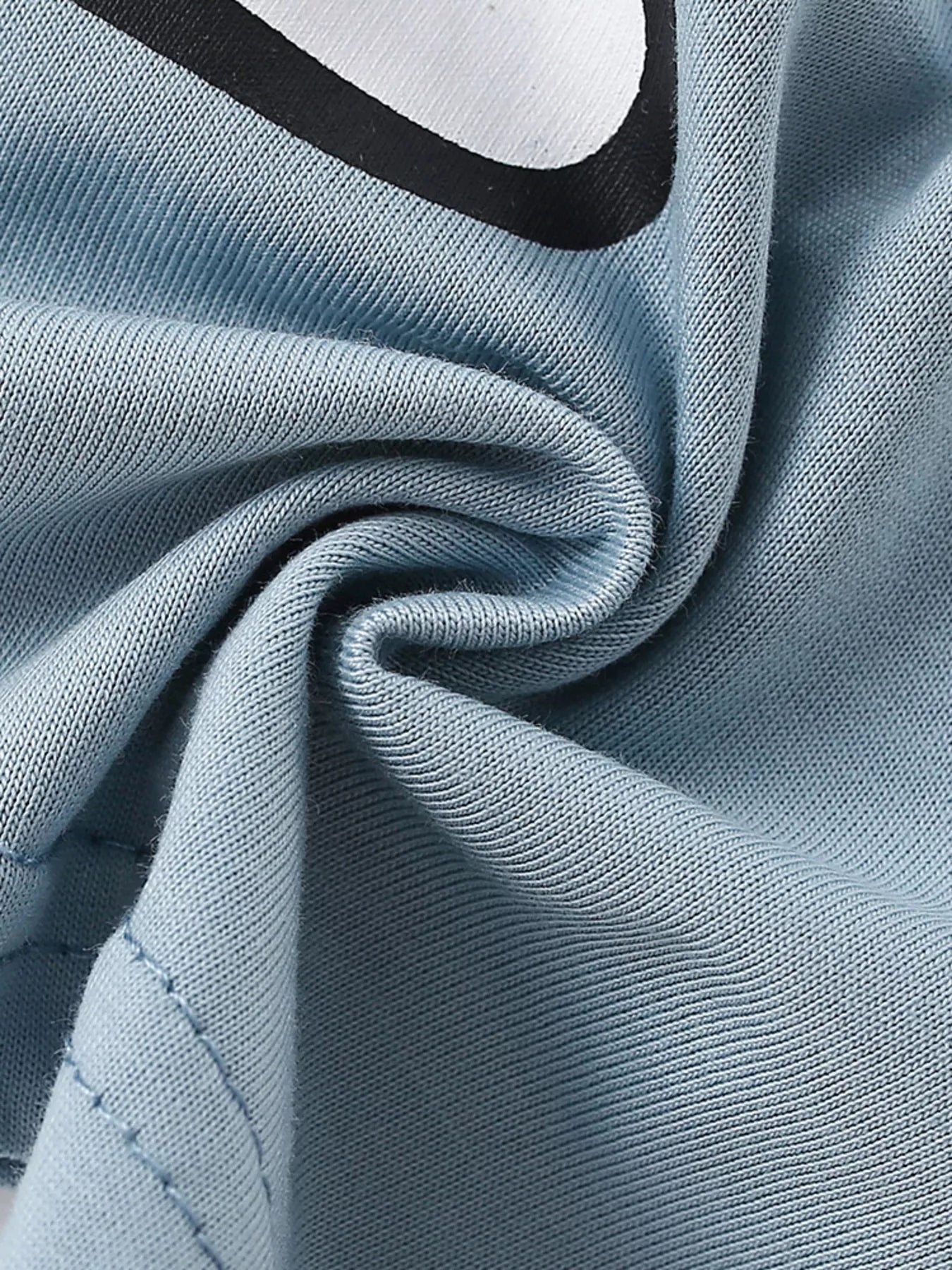 Close-up of soft light blue fabric texture with a partial edge of the bear graphic
