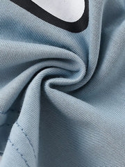 Close-up of soft light blue fabric texture with a partial edge of the bear graphic
