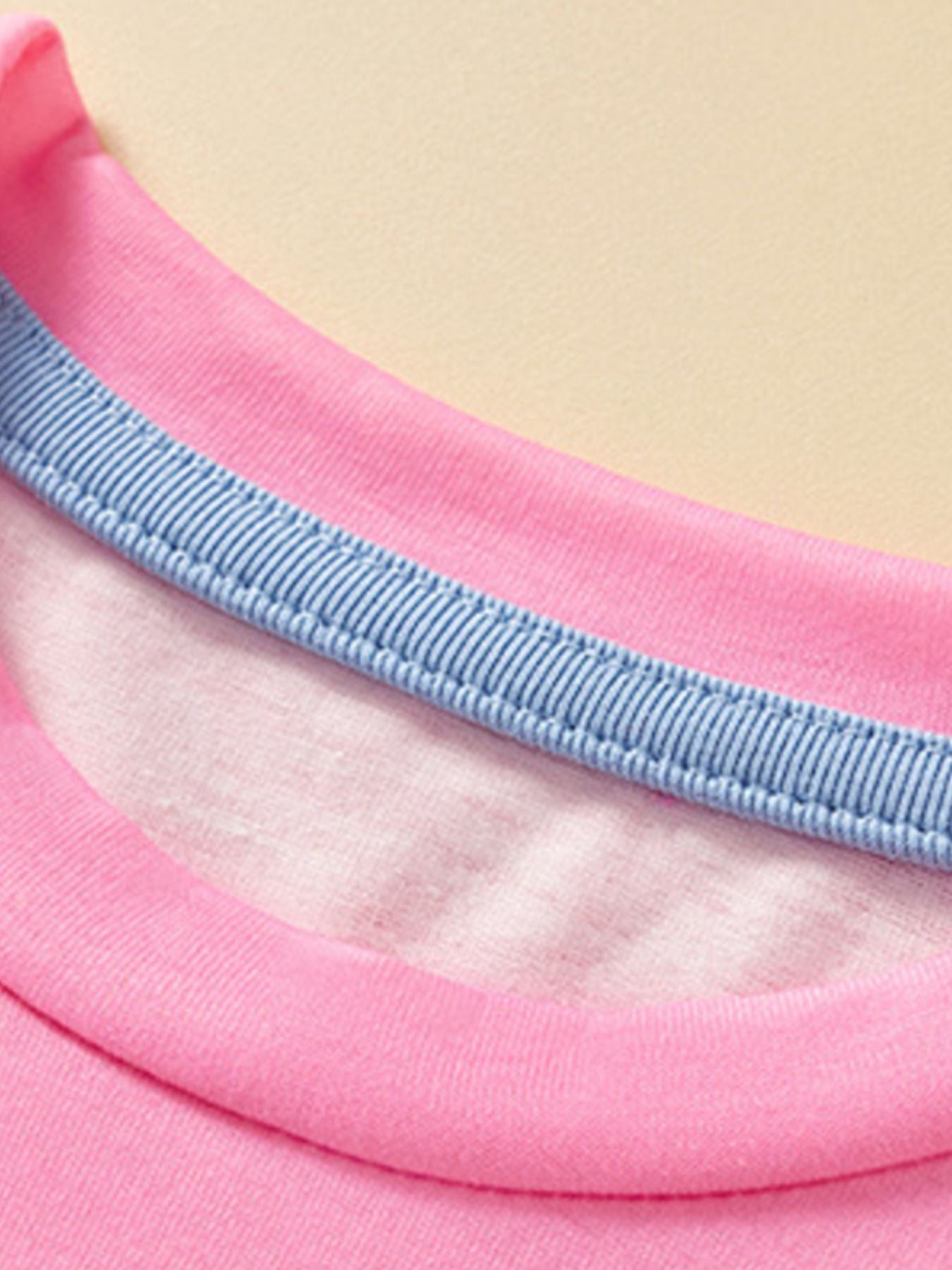 Close-up of the pink round neckline with a light blue inner trim and stitching