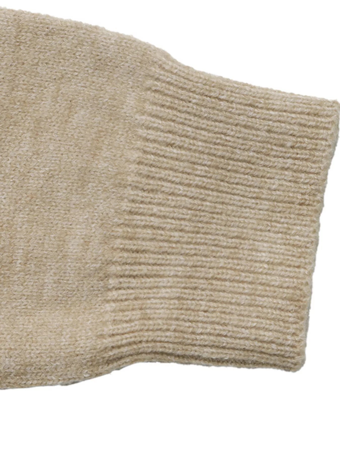 Close up of beige ribbed cuff on color block knit sweater sleeve.