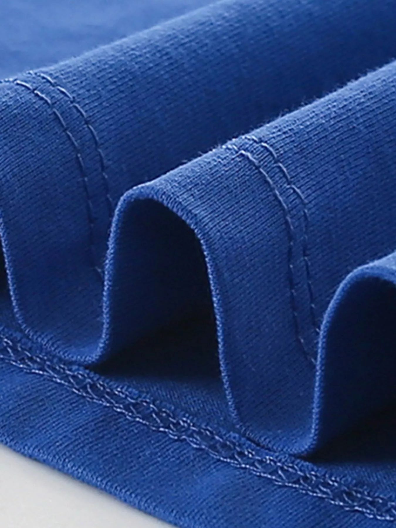 Close view of the stitched hem and folded fabric on an indigo children's t shirt
