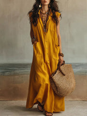 Gold sleeveless button down linen maxi dress in full front view holding a woven tote