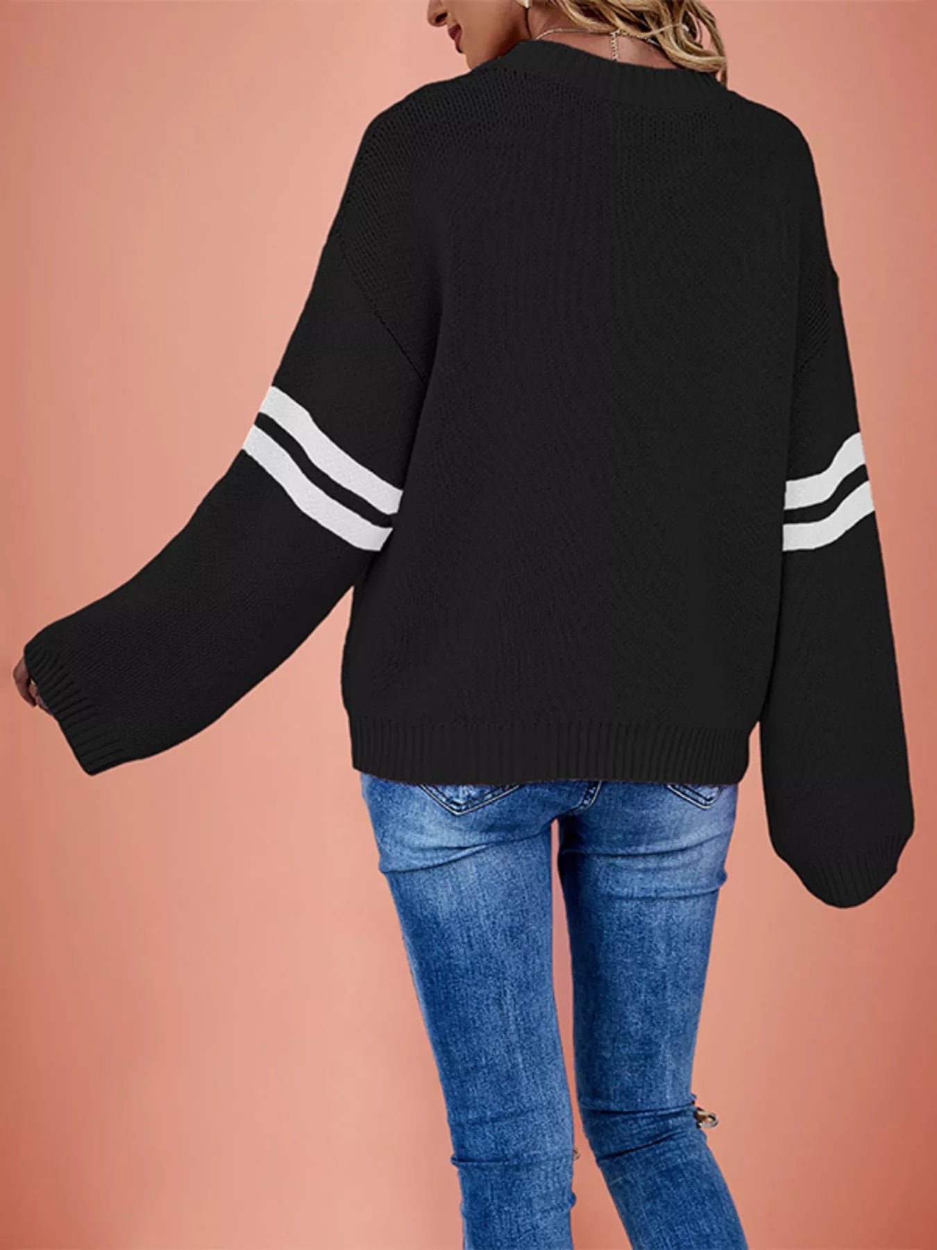 Back view of a black dropped shoulder sweater with white striped sleeves