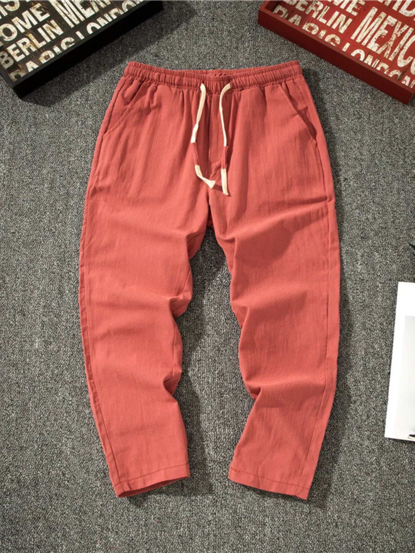 Men's red loose-fit pants with a drawstring waist and pockets.