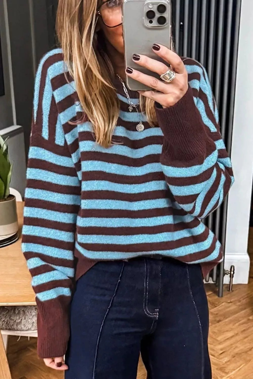 Mirror selfie front view of the blue and brown striped sweater with brown cuffs and dark jeans