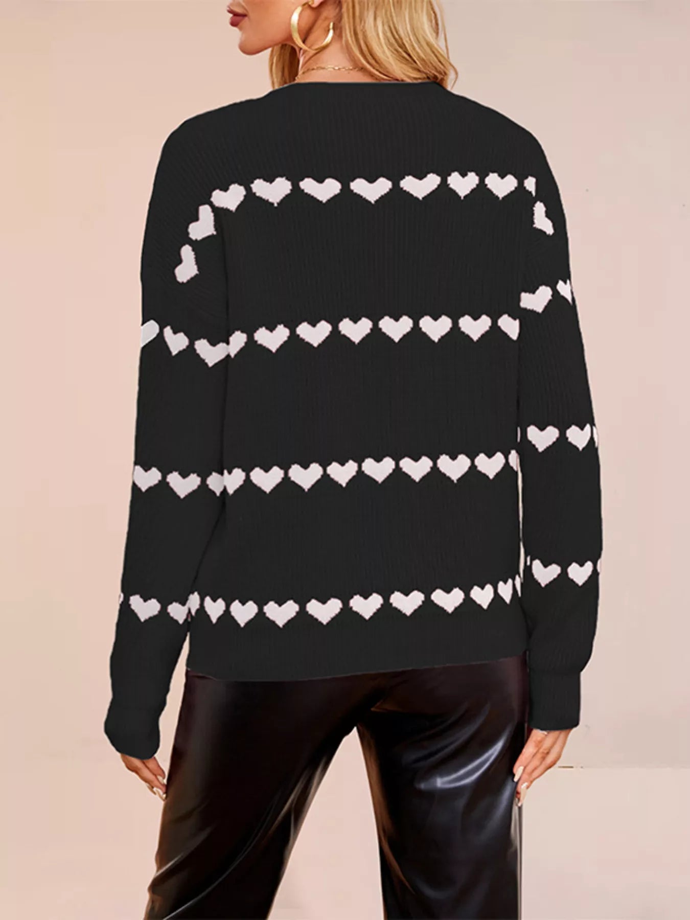 Back view of a black dropped shoulder sweater with rows of white hearts