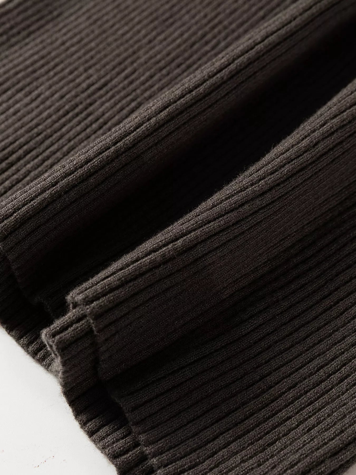 Close up of coffee brown ribbed hem and folded fabric on sweater vest