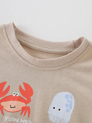Close-up of the tan ribbed neckline and crab and jellyfish graphics on a children's ocean tee