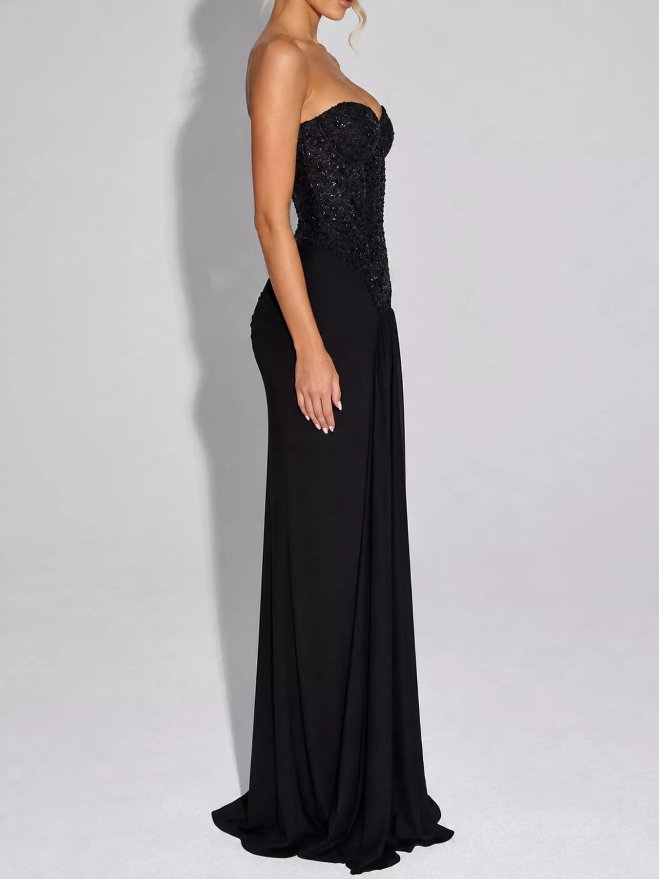 Black strapless sequin corset maxi dress on model, full length side profile in studio