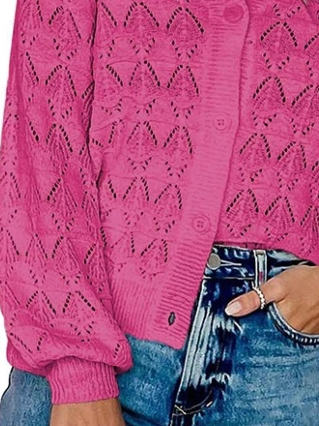 Side close view of bright pink openwork knit cardigan showing button front and hem.