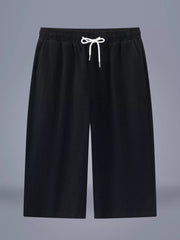 Men's black cropped casual pants with a drawstring waist and pockets.
