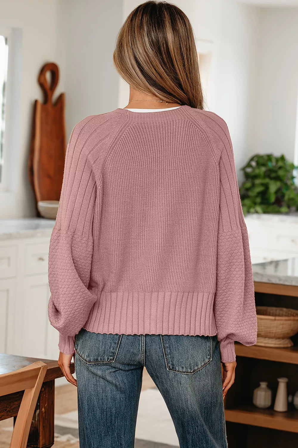 On-model back view of a dusty pink V-neck cardigan with a ribbed hem and long sleeves