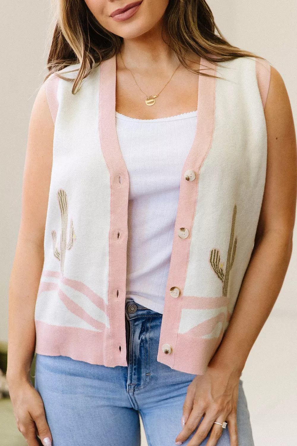 On-model front view of the cream cactus sweater vest worn open over a white top