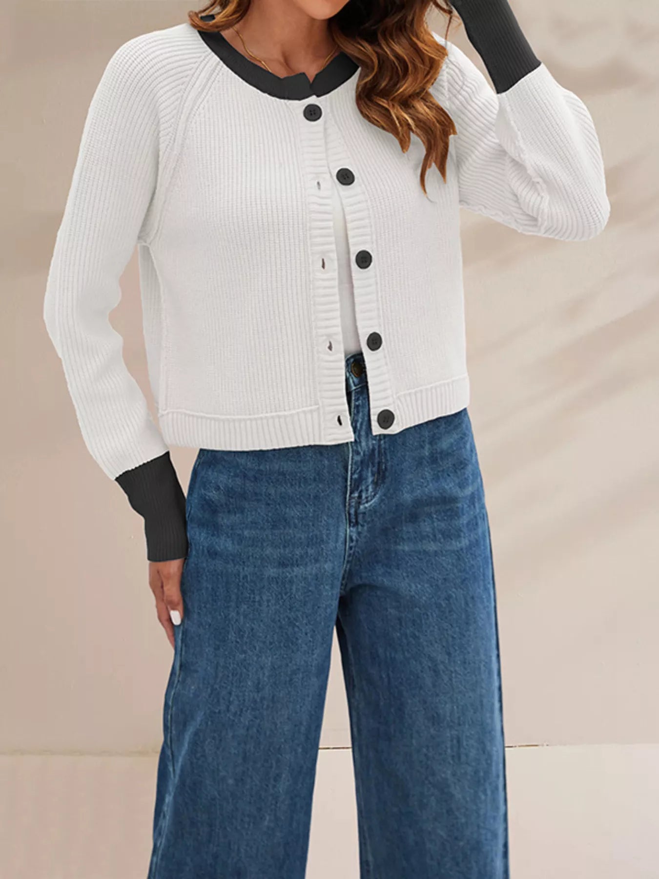 On-model side front view of the white cardigan with black trim and one arm raised