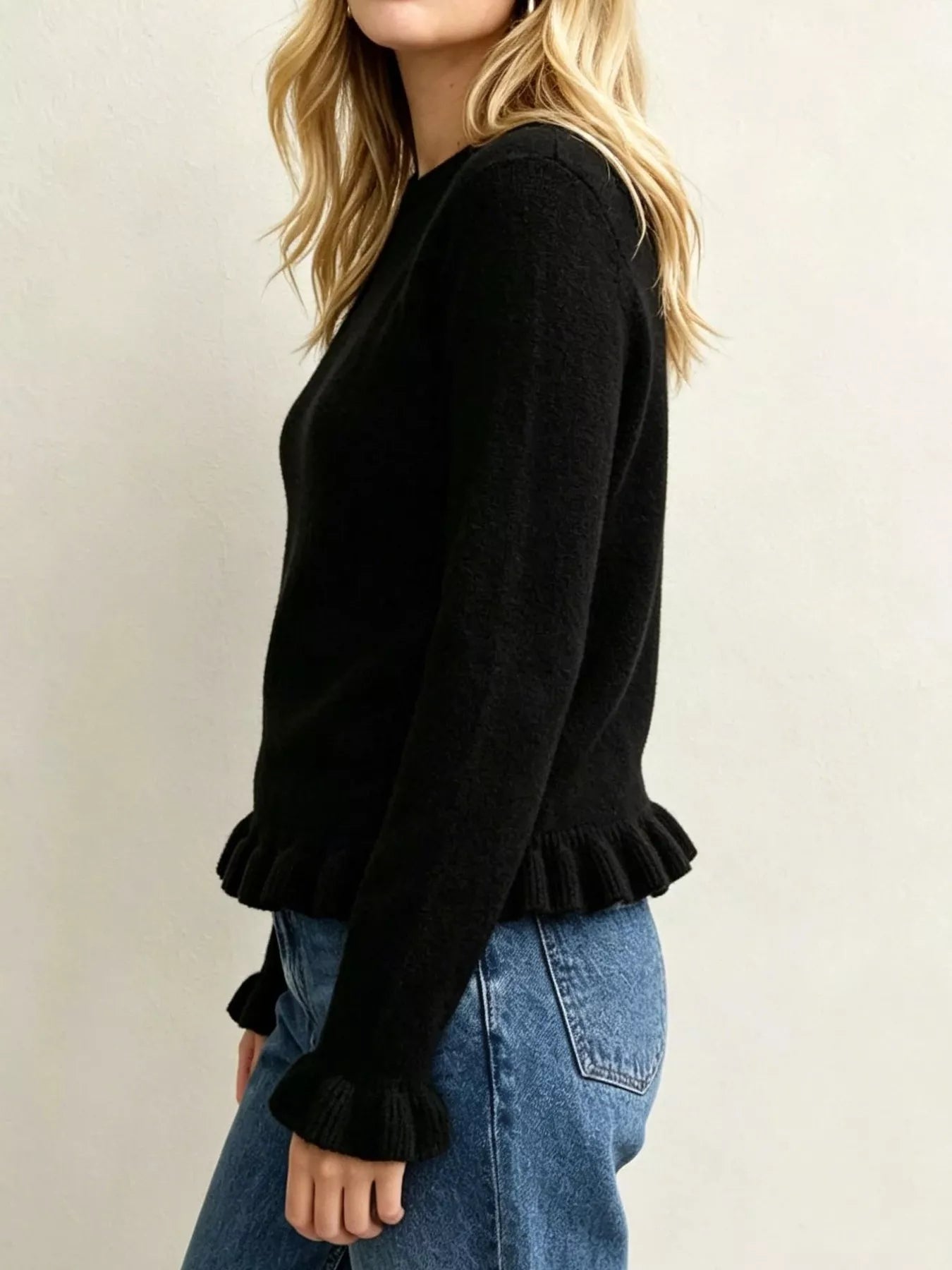 Side view on-model of black crew neck sweater with ruffled hem and cuffs