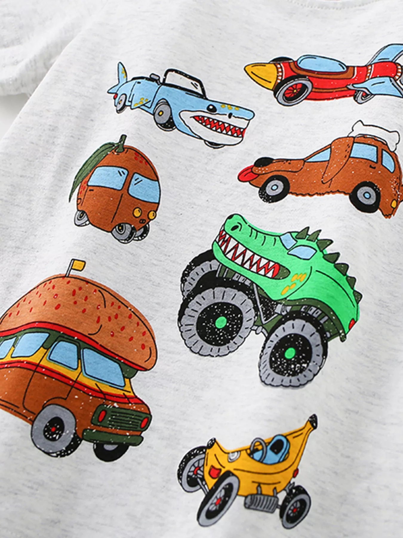 Angled close-up of the cartoon vehicle prints showing a green dinosaur monster truck and burger van