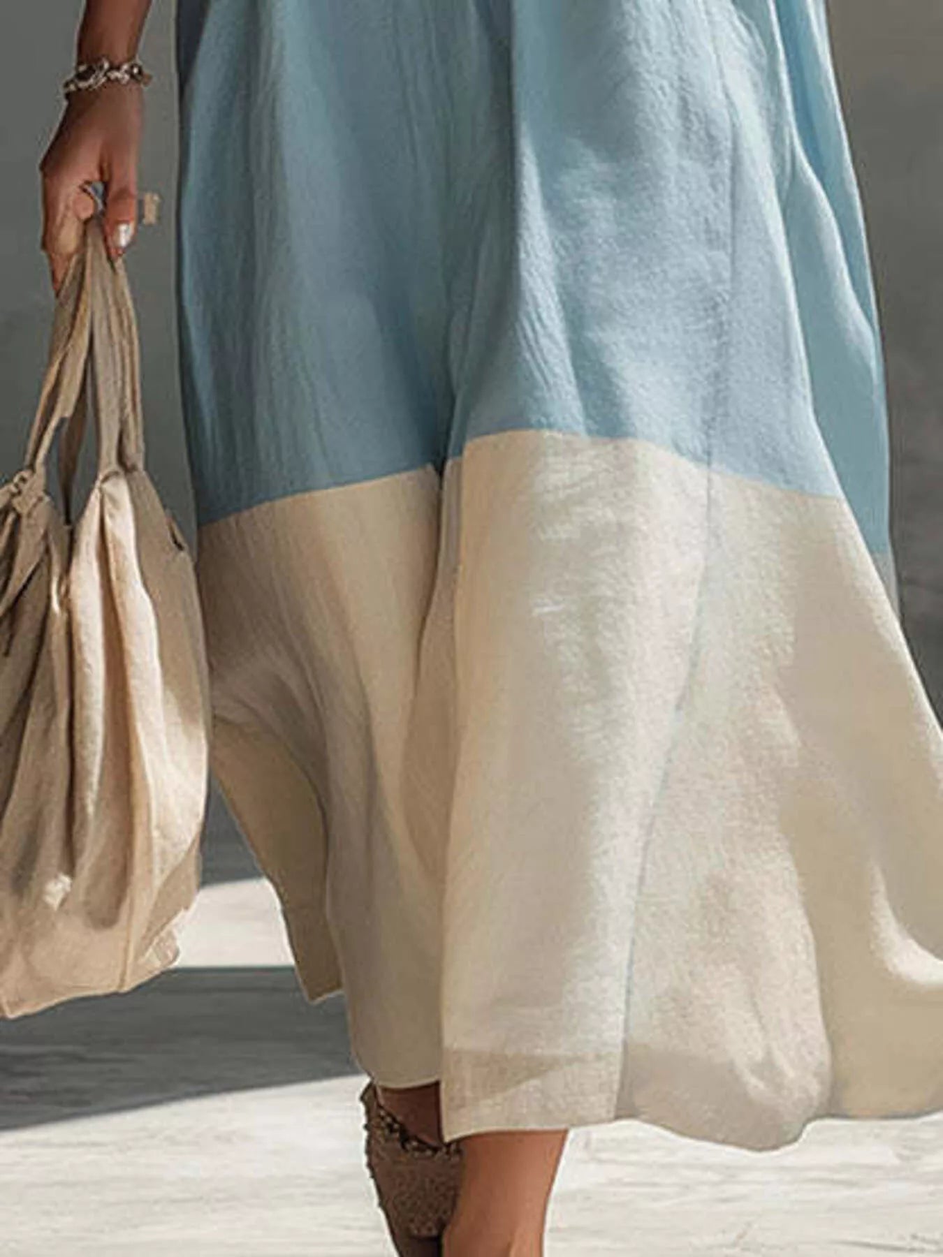 Close lower view on model of light blue color block midi dress showing cream hem panel