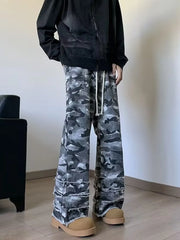Three-quarter view of men's grey camouflage wide leg jeans with frayed raw hems, styled on model.