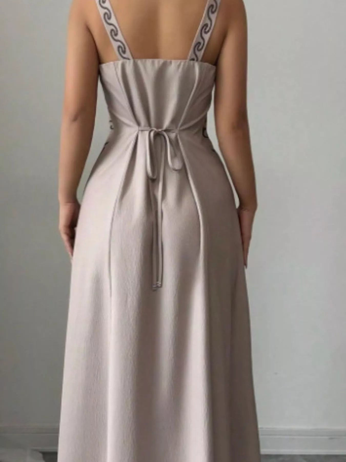 Close back view of gray maxi dress showing tied waist and patterned straps