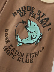 Close-up of circular fishing fish graphic and lettering on caramel children's short sleeve t-shirt