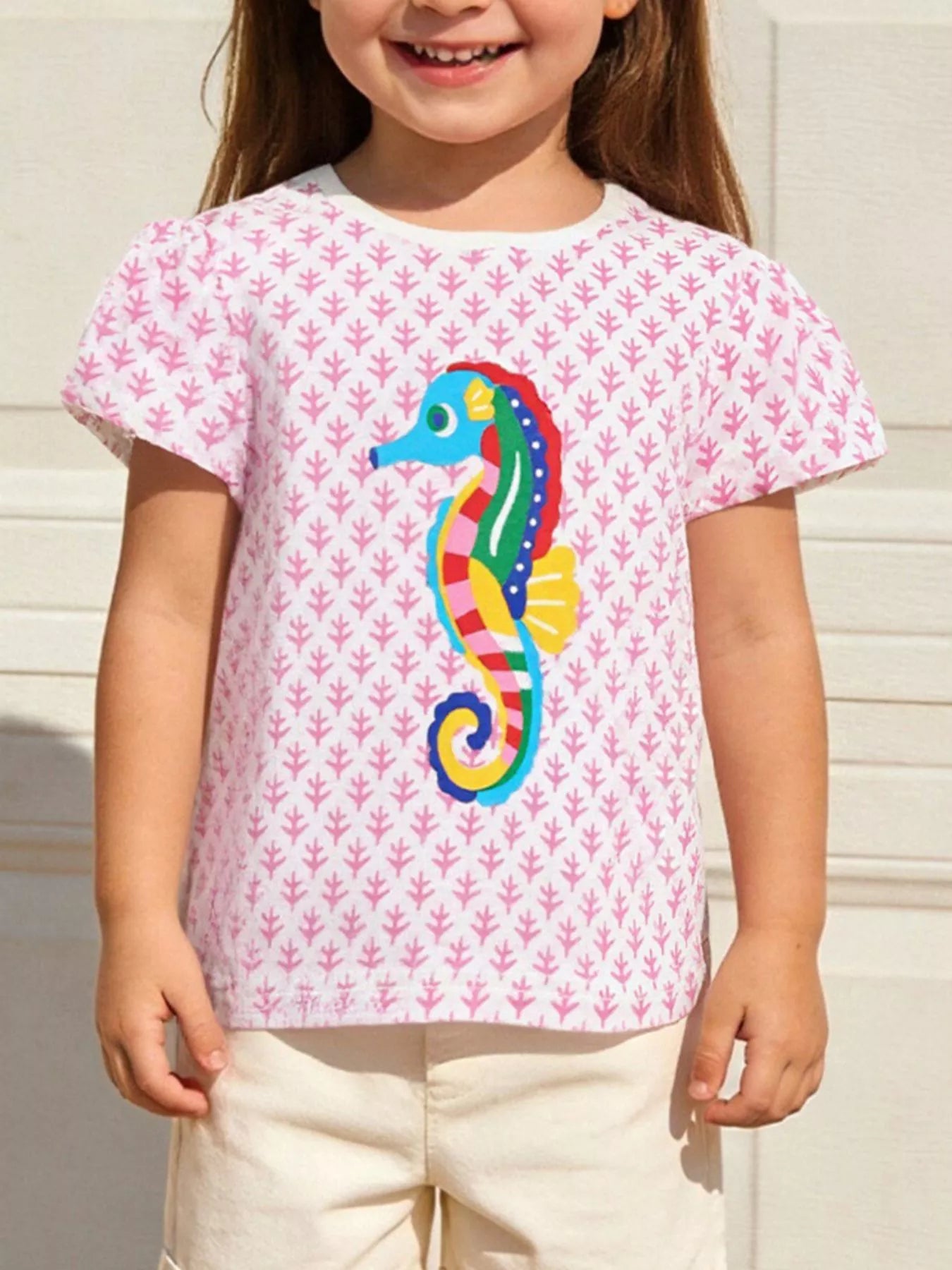 Front view of a blush pink children's tee with a colorful seahorse and small pink pattern