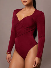 Three quarter front view of burgundy ruched surplice long sleeve bodysuit on model