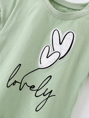 Close view of the white heart appliques and black lovely lettering on the sage children's T-shirt