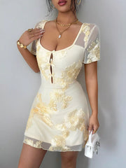 Front view on model of milky white floral mesh short sleeve mini dress with bow front detail