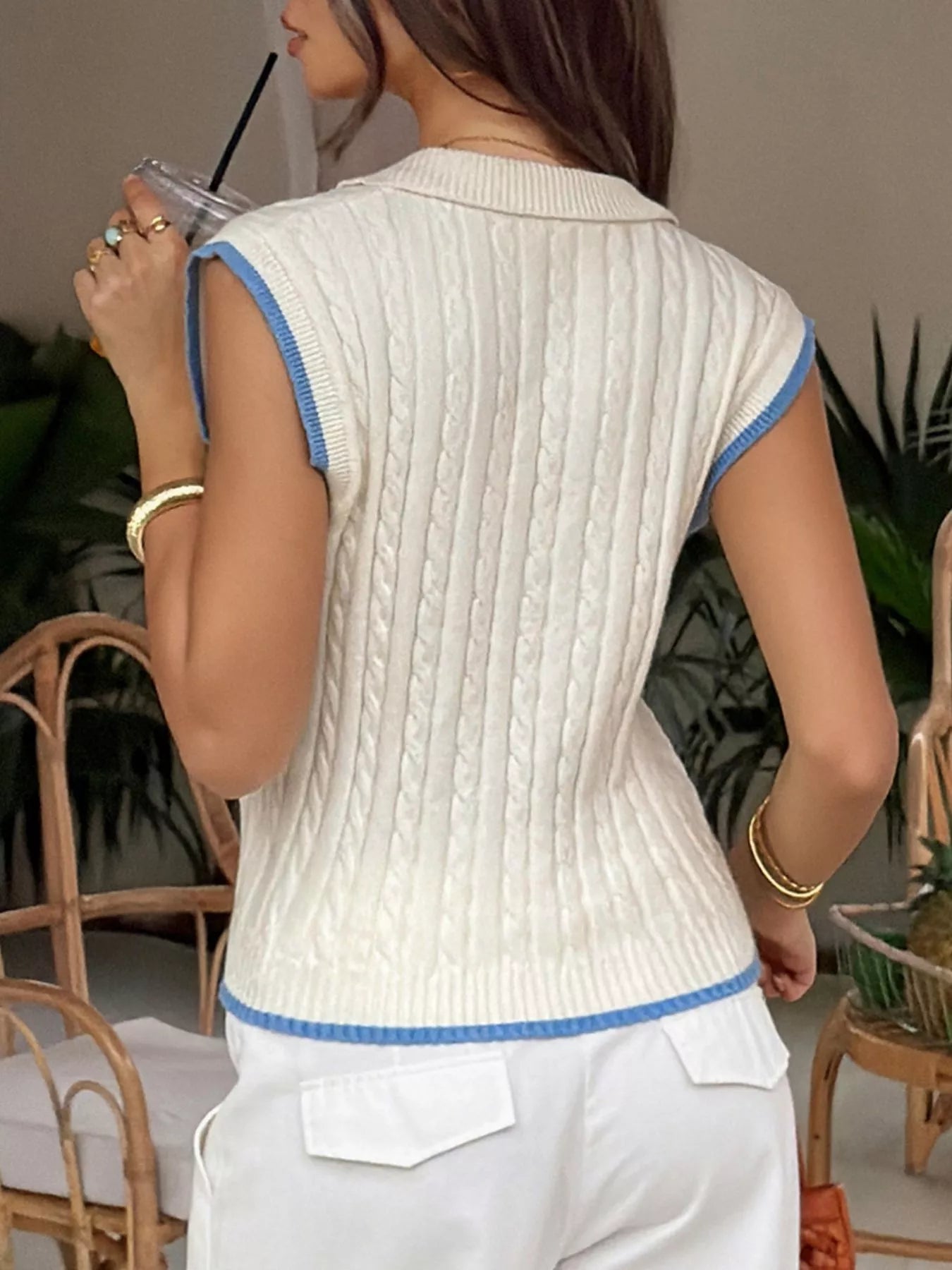Back view of the cream cable knit vest with blue trim on the armholes and hem