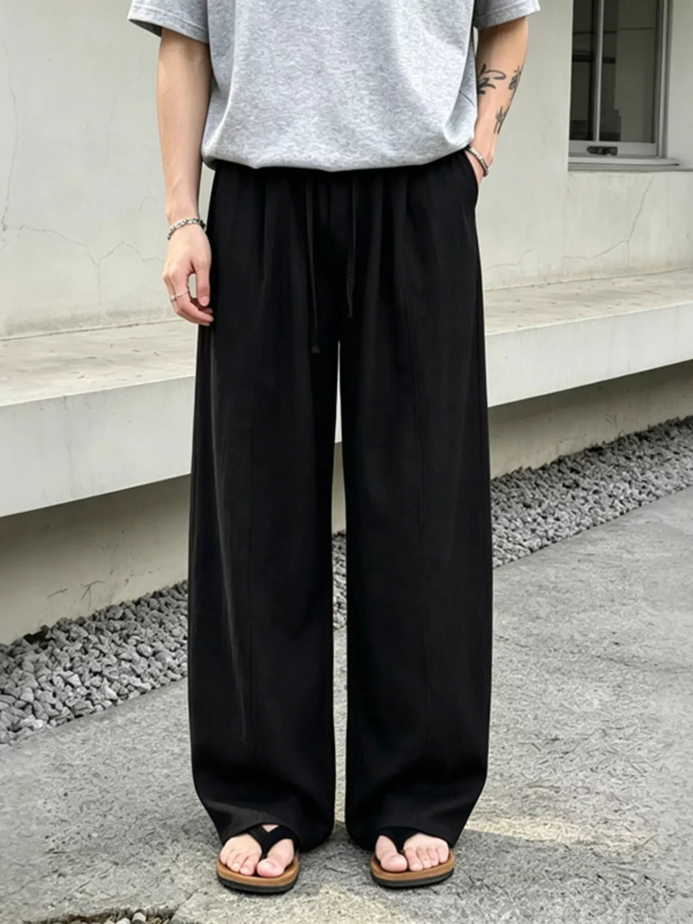 Men's wide-leg pants with a drawstring waist and pockets in the black color.
