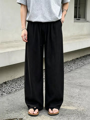 Men's wide-leg pants with a drawstring waist and pockets in the black color.