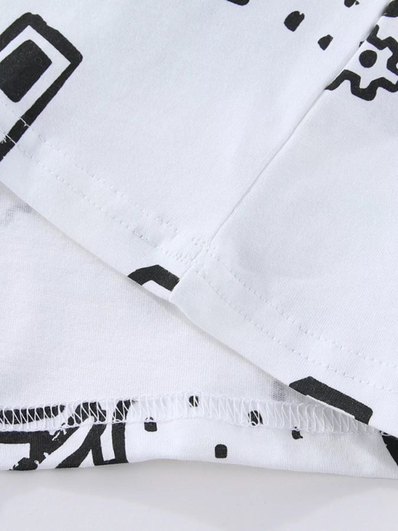 Close-up of the white hem and sleeve seam stitching beside a black vehicle print