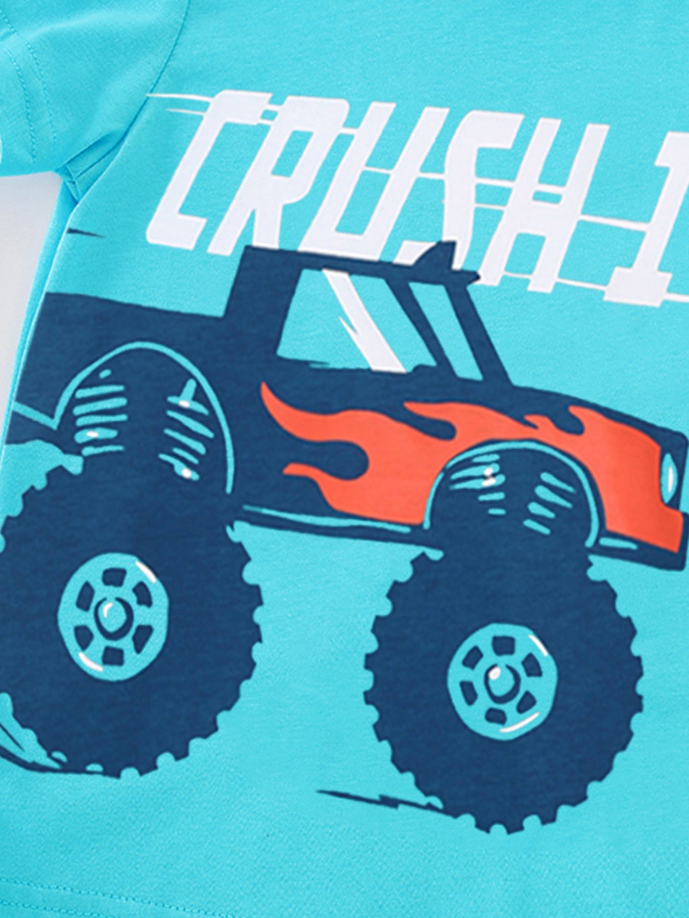 Detail view of the large monster truck graphic with flame details on a children's pastel blue t-shirt