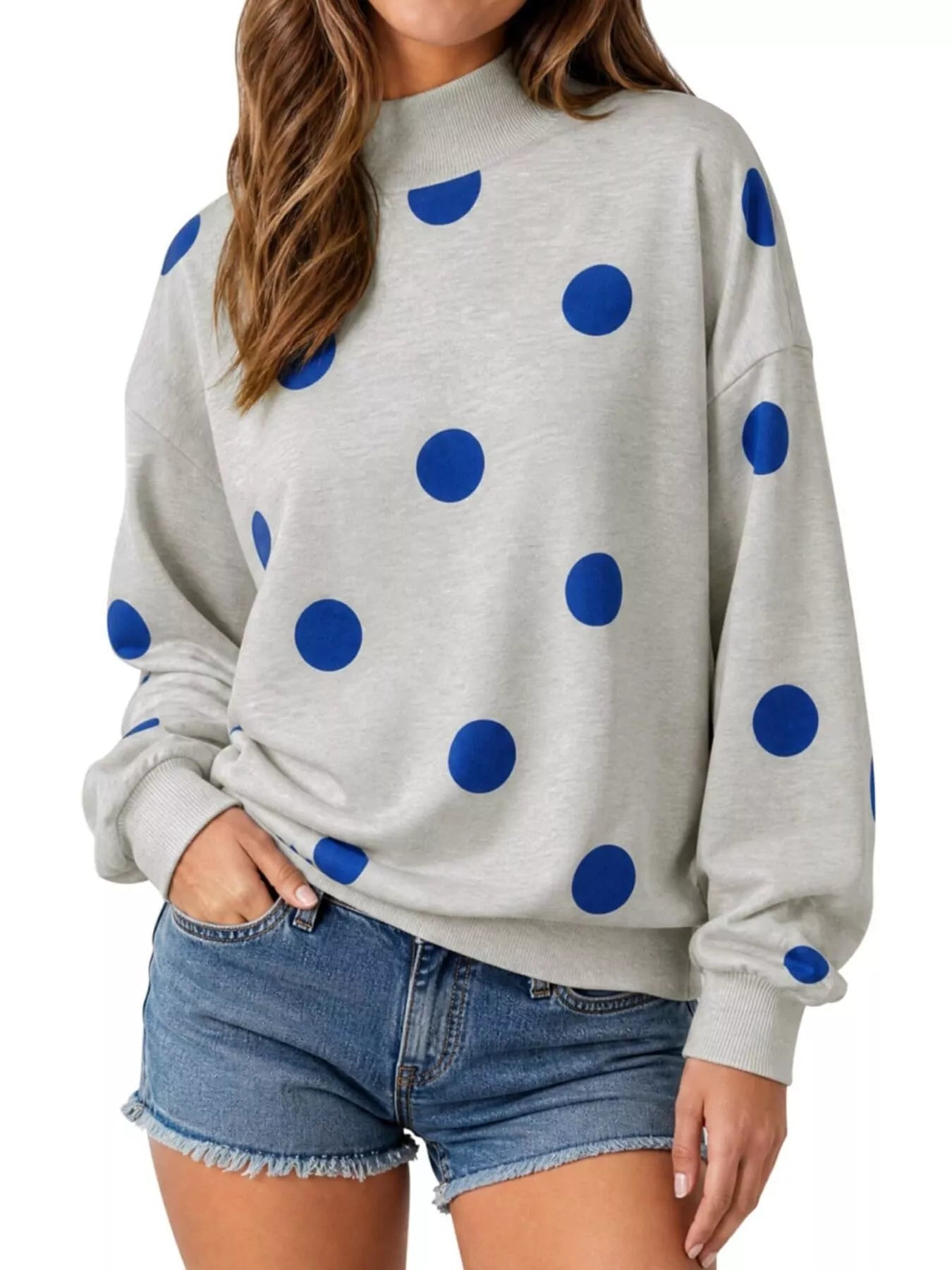 Front view of light gray mock neck oversized sweatshirt with large blue polka dots on model